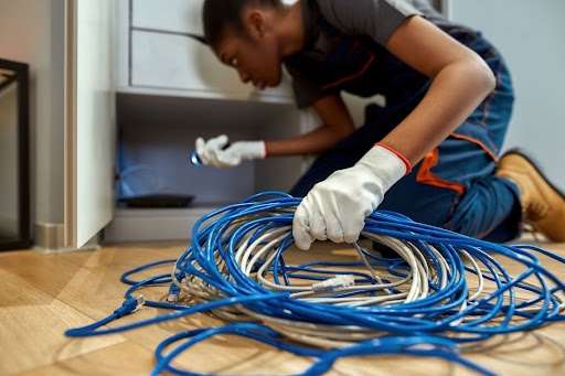 Electrician holding cable in one hand while checking outlet with a flashlight